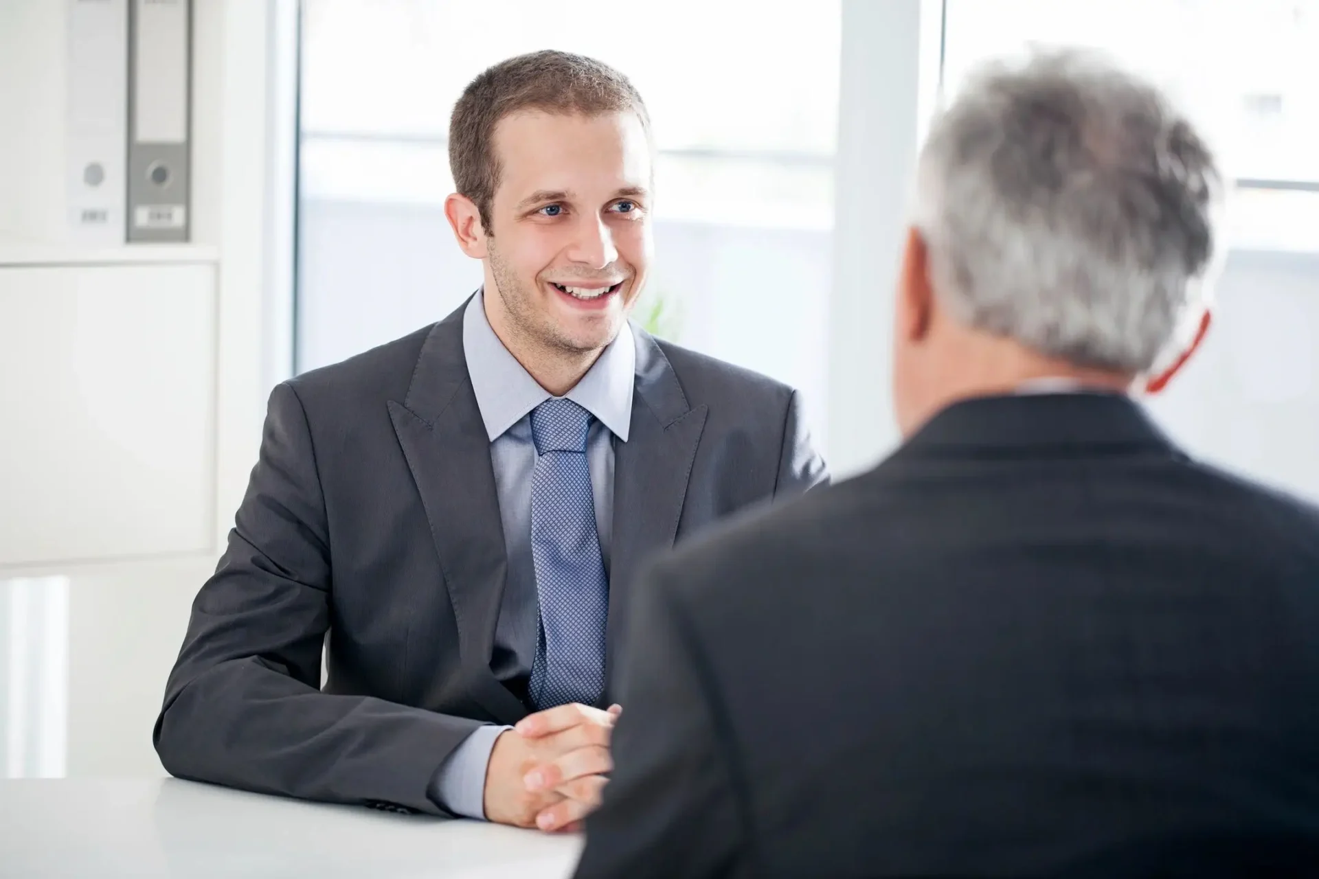 A man in suit and tie shaking hands with another man.