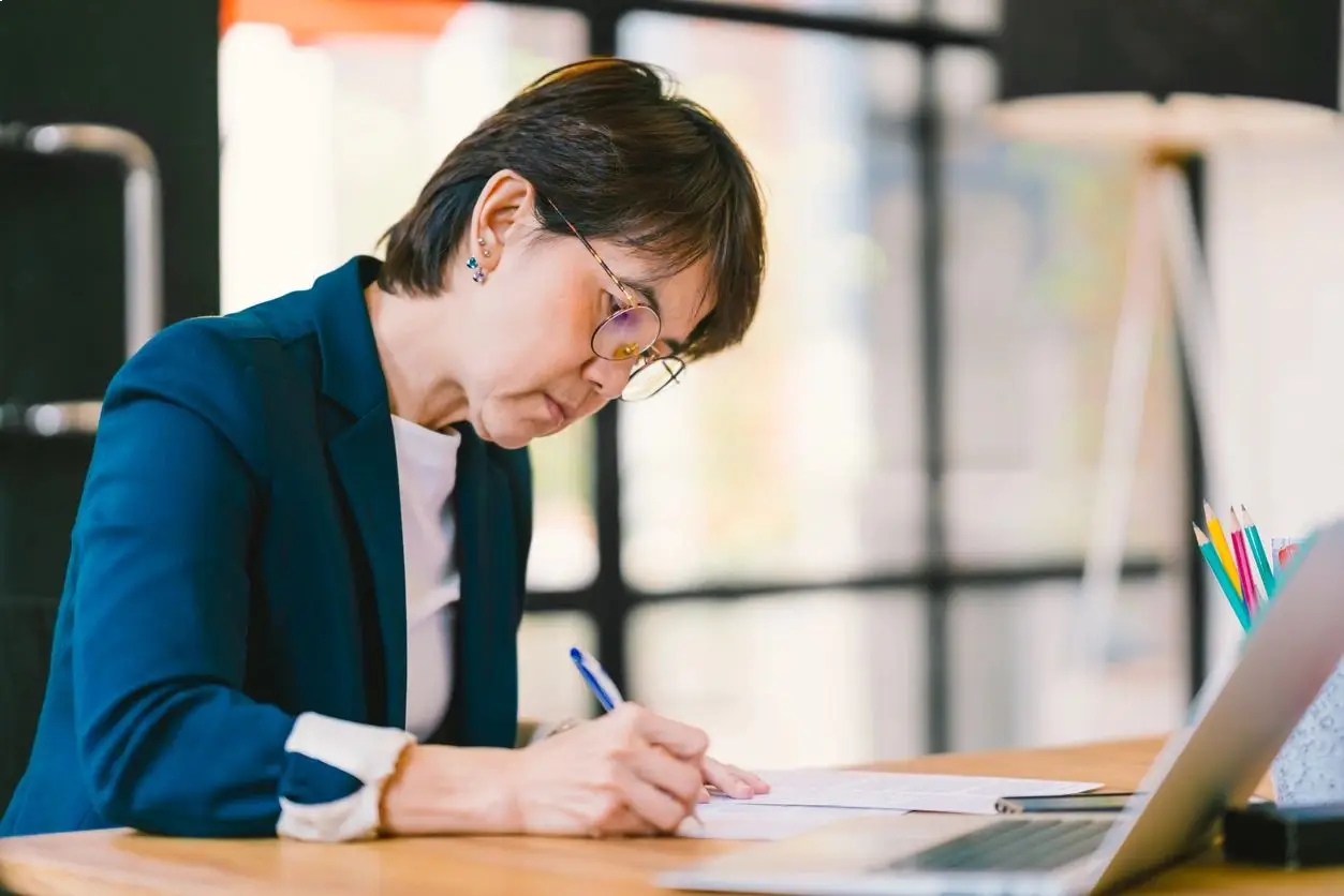 A woman is writing on paper at the table