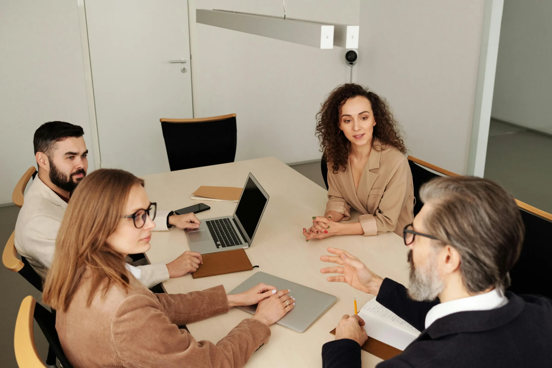 Three people sitting at a table with laptops.